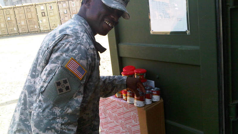 Army Sgt. 1st Class Maurice Blackburn pick up snacks donated by USO at the centralized distribution container.
