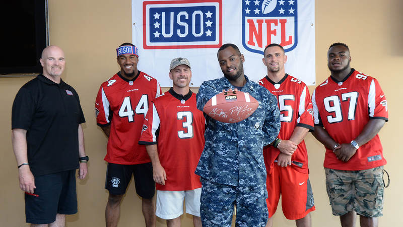 A sailor shows off a football signed by Atlanta Falcons coach Dan Quinn, left, and players Vic Beasley, Matt Bryant, Paul Worrilow and Grady Jarrett during a weeklong USO/NFL tour to Guam and Hawaii.