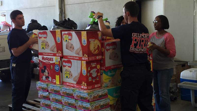 USO staffers Felice Kelly Gillum and Nicole Lewis assist Gulfport Fire Department sort relief supplies from the USO Gulf Coast supply drive for flood victims in Louisiana.