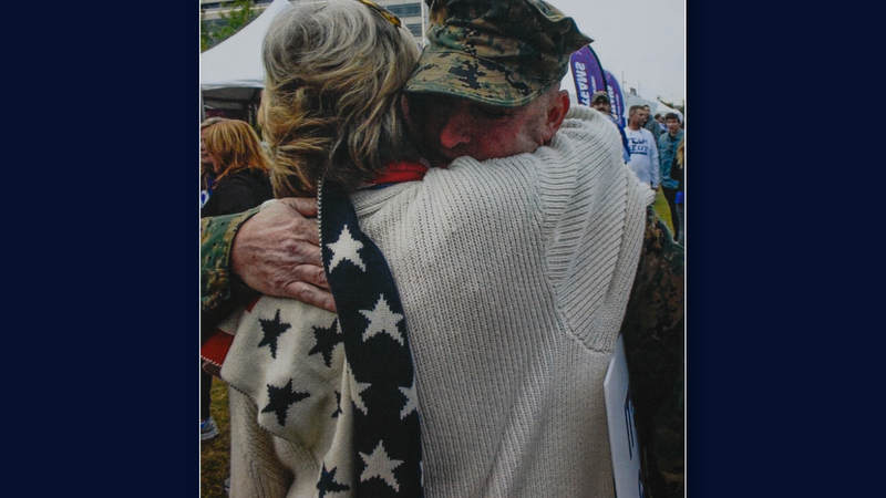 Suzanne Mitchell hugs a service member.