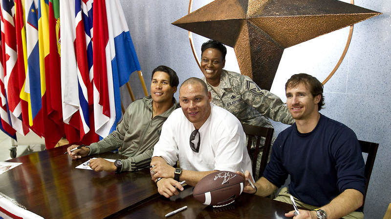 Donnie Edwards, Billy Miller and Drew Brees pose for a photo with U.S. Air Force Senior Master Sgt. Abigail Davis, from Tallahasse, FL at the NATO Allied Air Command in Izmir, Turkey, March 25, 2010.