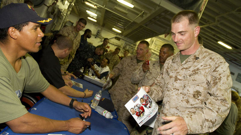 NFL and USO tour veteran Donnie Edwards signs an autograph for Marines and Sailors of the USS Nassau, March 28, 2010. Edwards is joined by fellow NFL players Drew Brees and Billy Miller, this marks the third USO tour for the trio, who will visit troops in Africa, Turkey and the Persian Gulf.