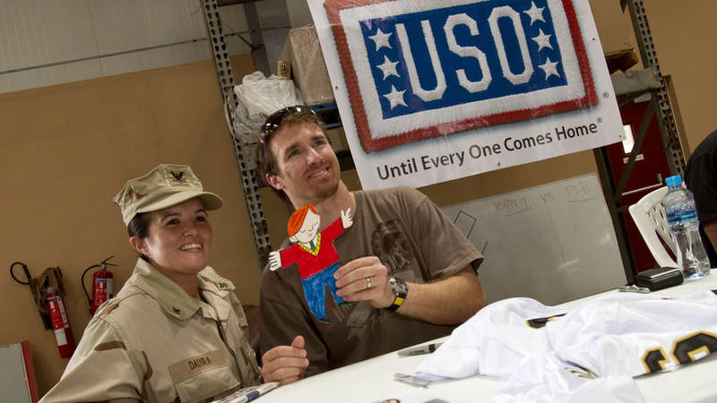 Most Valueable Player” Drew Brees poses for a photo with PS2 Lisa Dadurn of Pensacola, FL during a USO visit to Dubaii on March 27, 2010. While taking the picture, Brees holds up “Flat Stanley”, a project of Dadura’s second grade niece in Ft. Worth, TX.