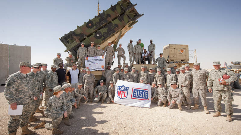 NFL players (L) Mario Williams-Houston Texans, Joe Thomas-Cleveland Browns (L-next to Williams), Jason Witten-Dallas Cowboys (center) and Vernon Davis-San Francisco 49ers (kneeling next to Witten) pose with the entire crew supporting the defensive missile system, March 3, 2010. On an eight-day, nine-base USO tour the four players are on a mission to visit with troops, sign autographs and boost morale.