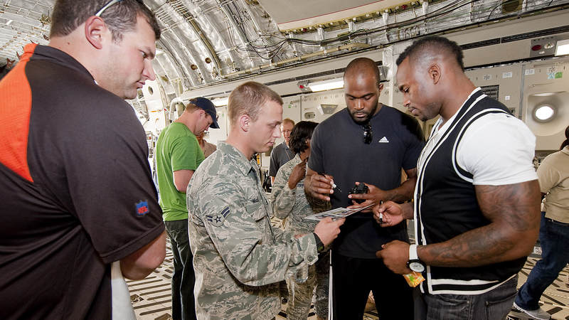NFL players (L-R) Joe Thomas-Cleveland Browns, Jason Witten-Dallas Cowboys (background-green), Mario Williams-Houston Texans (R-Center), and Vernon Davis-San Francisco 49ers (R) sign autographs for the crew of a C-17 cargo aircraft at the airbase, March 3, 2010.