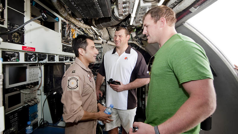 NFL players Joe Thomas-Cleveland Brown (C) and Jason Witten-Dallas Cowboys (R) get a tour of an RC 135/JSTARS aircraft from a service member, March 3, 2010. The two Pro Bowl players are joined by fellow Pro Bowlers Vernon Davis-San Francisco 49ers and Mario Williams-Houston Texans on their first USO tour, traveling to nine bases in eight days the players will sign autographs, participate in meet and greets and extend their gratitude to troops.
