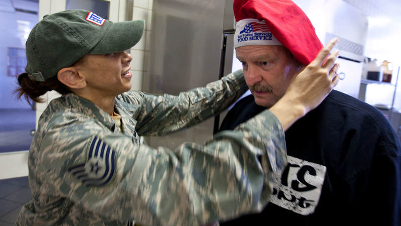 Minnesota Vikings head coach Brad Childress gets some help after trading hats with TSgt Tamala Williams, a cook at a dining facility at Ramstein Air Base in Germany, during a USO tour stop on June 30, 2010.