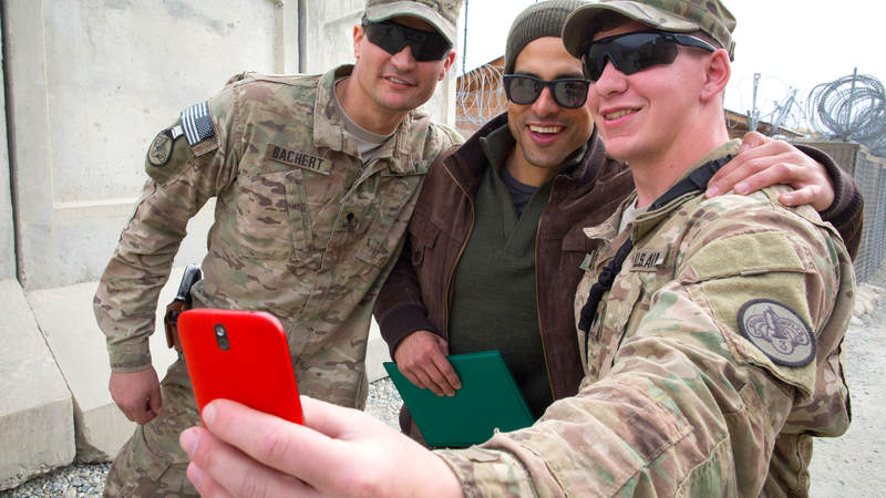Actor Adam Rodriguez poses for a selfie with two service members during a USO tour stop in Afghanistan.