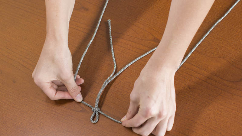 4. Find the middle point of the rest of the cord. Tied this middle point about a half an inch from the folded end of your shorter, folded piece of cord.