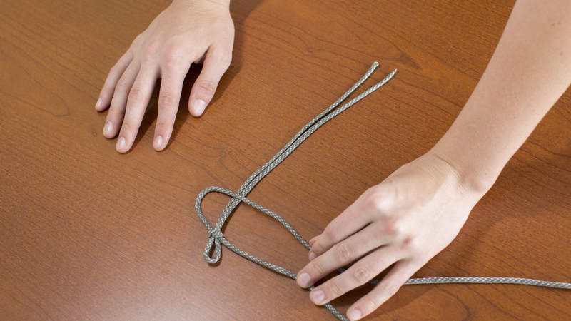 5. Take the right long strand of cord and cross it over to the left.