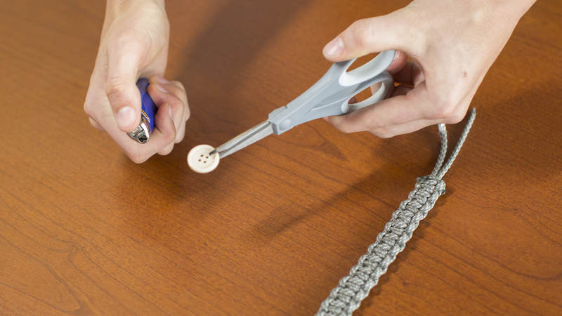13. Holding the edge of the button with the ends of your scissors, melt the center of the button for 2-3 seconds. Immediately after melting, use a pen to poke a hole through the button. You might have to repeat this process a couple of times.