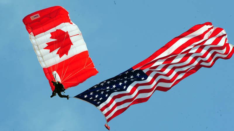 A member of the Canadian SkyHawks parachutes with the American flag.