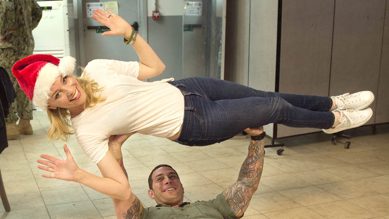 A service member bench presses Elizabeth Banks during her 2015 trip to Camp Lemonnier in Djibouti.