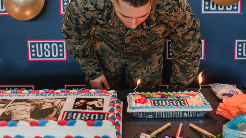 Marine Staff Sgt. Dustin Johnson, 29, blows out the candles on his birthday cake. USO photo by Amber Craig.