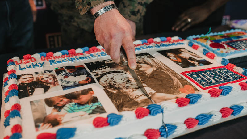 Marine Staff Sgt. Dustin Johnson cuts the ceremonial first slice of his extra-special birthday cake. USO photo by Amber Craig.