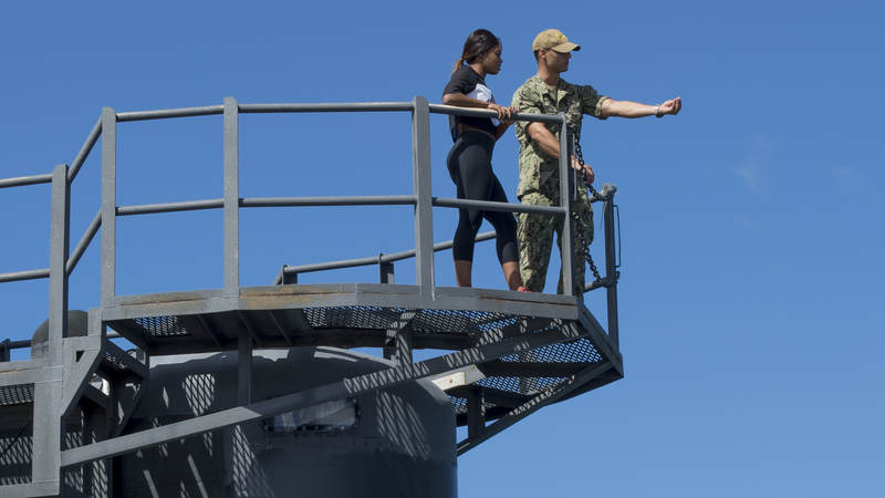 Navy Lt. j.g. Caleb Mazzola shows Gabby Douglas the Vertical Launch Systems (VLS) from the sail of the Asheville.