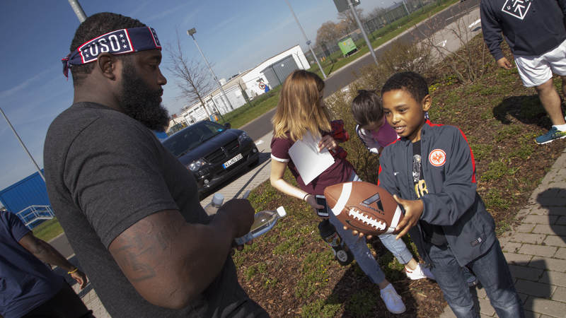 Carolina Panthers defensive end Mario Addison signs and autograph for a young fan in Germany during the 2018 USO-NFL tour.