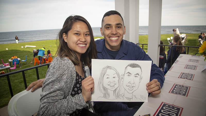 Navy Petty Officer Third Class Elvin Velez and his wife Kim show off their caricature drawing done by Mad Magazine contributor Sam Viviano during a USO barbecue at U.S. Coast Guard Station Point Judith Friday. USO Photo by Joseph Andrew Lee