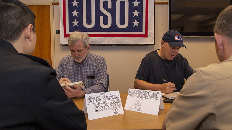 Sam Viviano, left, and Jeff Bacon, right, draw caricatures and cartoons for Navy corpsmen and nurses at Naval Health Clinic New England Friday. USO Photo by Joseph Andrew Lee