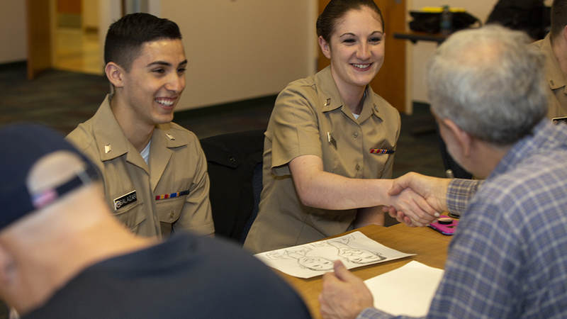 Navy Hospital Corpsmen Aaron Salazar and Kayla Deveno from Naval Health Clinic New England enjoy having their caricature drawn by Mad Magazine contributor Sam Viviano, Friday morning during the USO National Cartoonists Society tour of New England Navy and Coast Guard installations. USO Photo by Joseph Andrew Lee