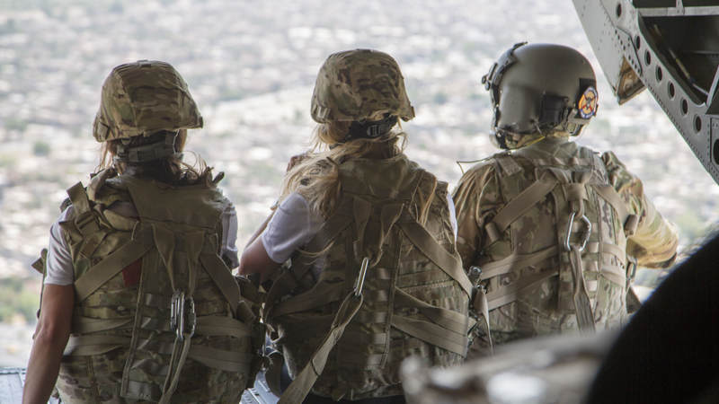Falcons cheerleaders Brianna Stade, center, and Alexandria Giannini look out over Baghdad, Iraq, from the back of a CH-47 Chinook helicopter during a USO tour to Iraq and Kuwait.
