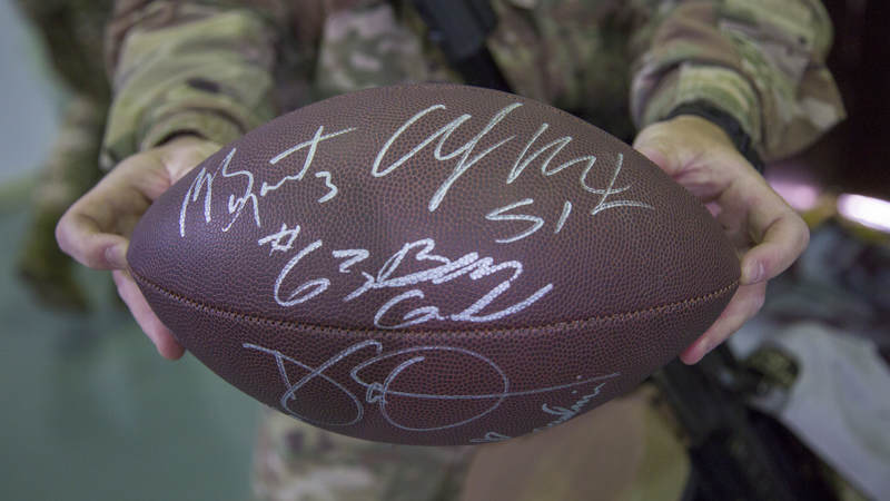 A service member holds a football that was signed by the entire Falcons group during a USO tour.