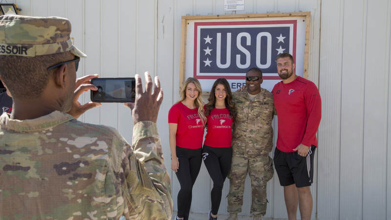 Falcons cheerleaders Brianna Stade, left, Alexandria Giannini and offensive lineman Ben Garland pose for a photo outside USO Erbil in Iraq.