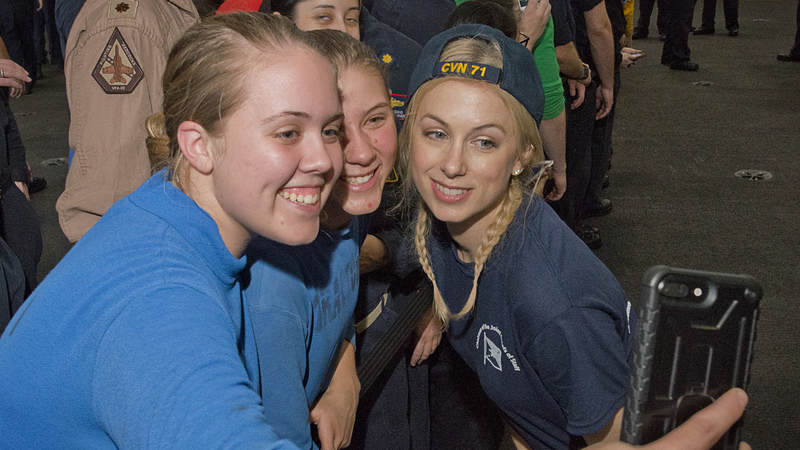 Iliza Shlesinger joins in on a selfie with service members aboard the USS Theodore Roosevelt during the Chairman's 2017 USO Holiday Tour.