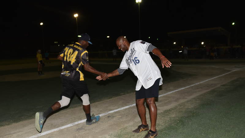 Former right fielder for the Kansas City Royals, Reggie Sanders, high-fives a service member during a pickup game of softball in Kuwait. USO Photo by Neal Preston.