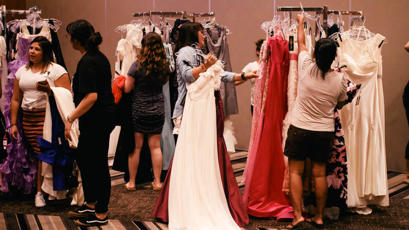 Military spouses and service members peruse ball gowns at USO Okinawa's Operation That's My Dress event, where dresses are free-of-charge. USO Photo by Ashley Perez.