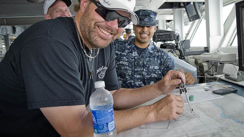 Musician Toby Keith flashes a smile as he takes a stab at understanding the navigation charts while touring the bridge of the aircraft carrier USS Abraham Lincoln.