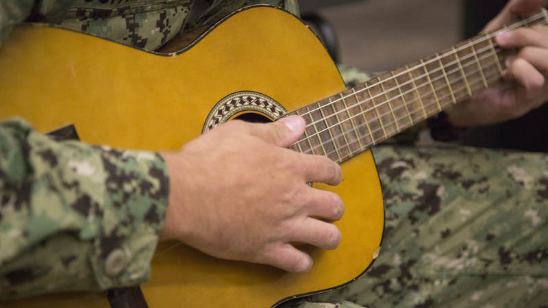 A Navy Seabee strums an acoustic guitar Feb. 8 during a late-night layover at USO Ontario.