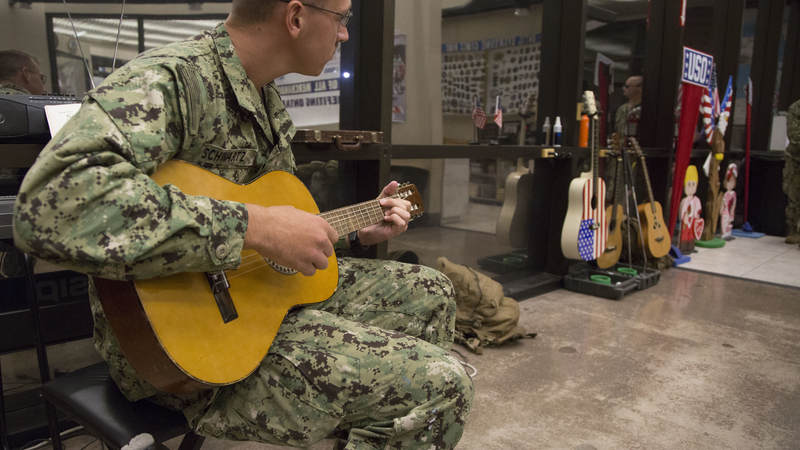 A Navy Seabee strums on an acoustic guitar Feb. 8 at 1:30 a.m. on a layover from Guam on his way home to Gulfport, Mississippi.